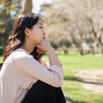 asian girl feeling sad by the park