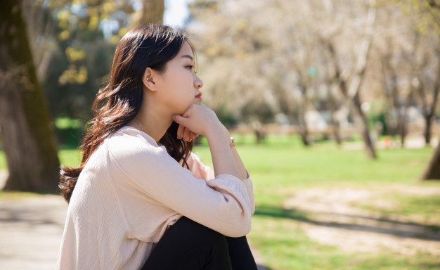 asian girl feeling sad by the park
